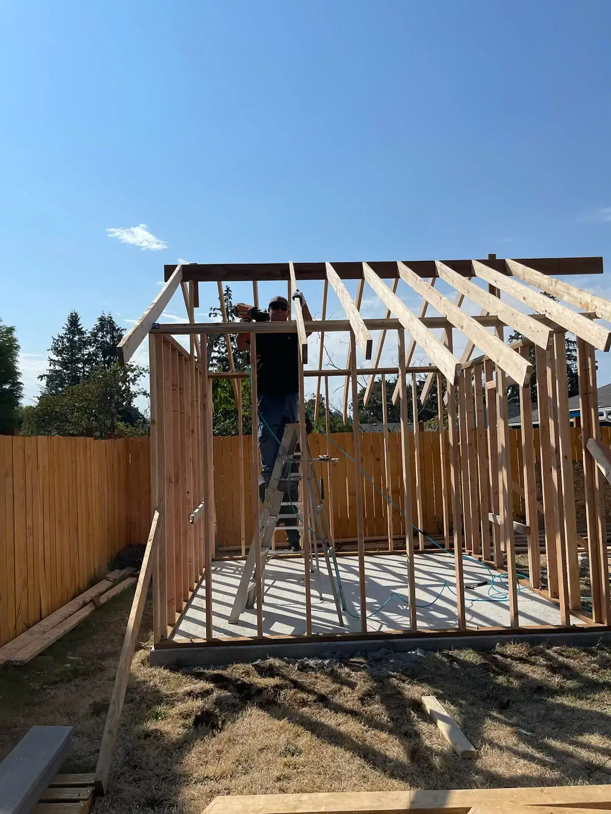 VMG crew member installing roof rafters on a framed backyard building