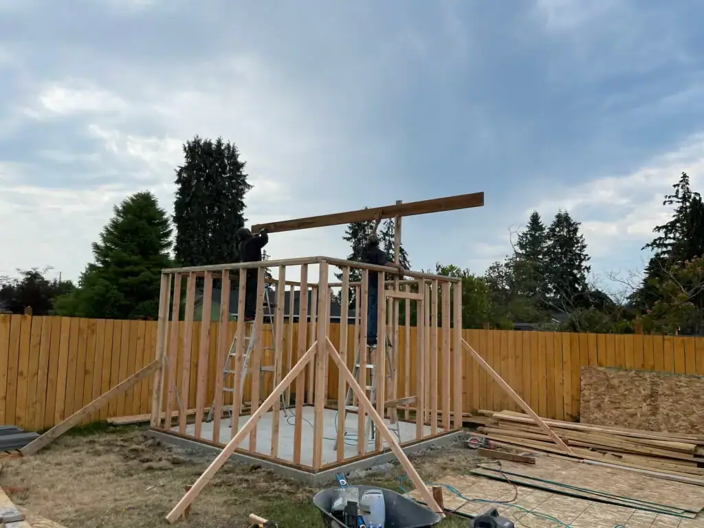 Two VMG crew members raising the ridge beam on a framed structure