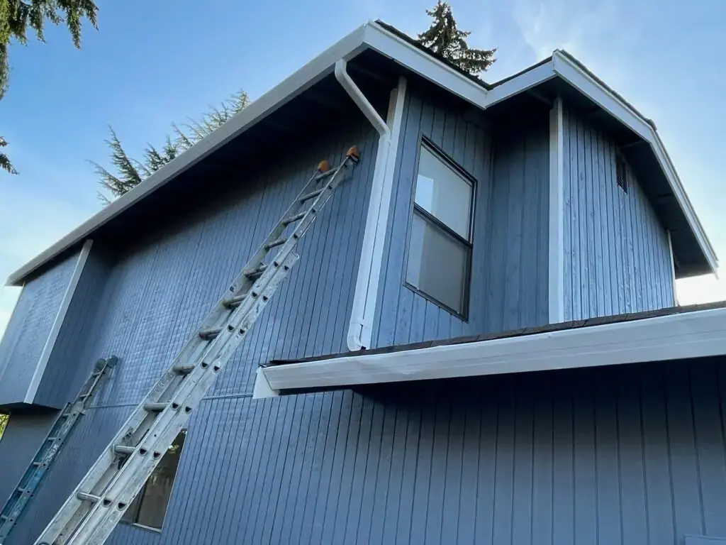 Two-story home exterior with blue siding and freshly installed white fascia and gutters by VMG